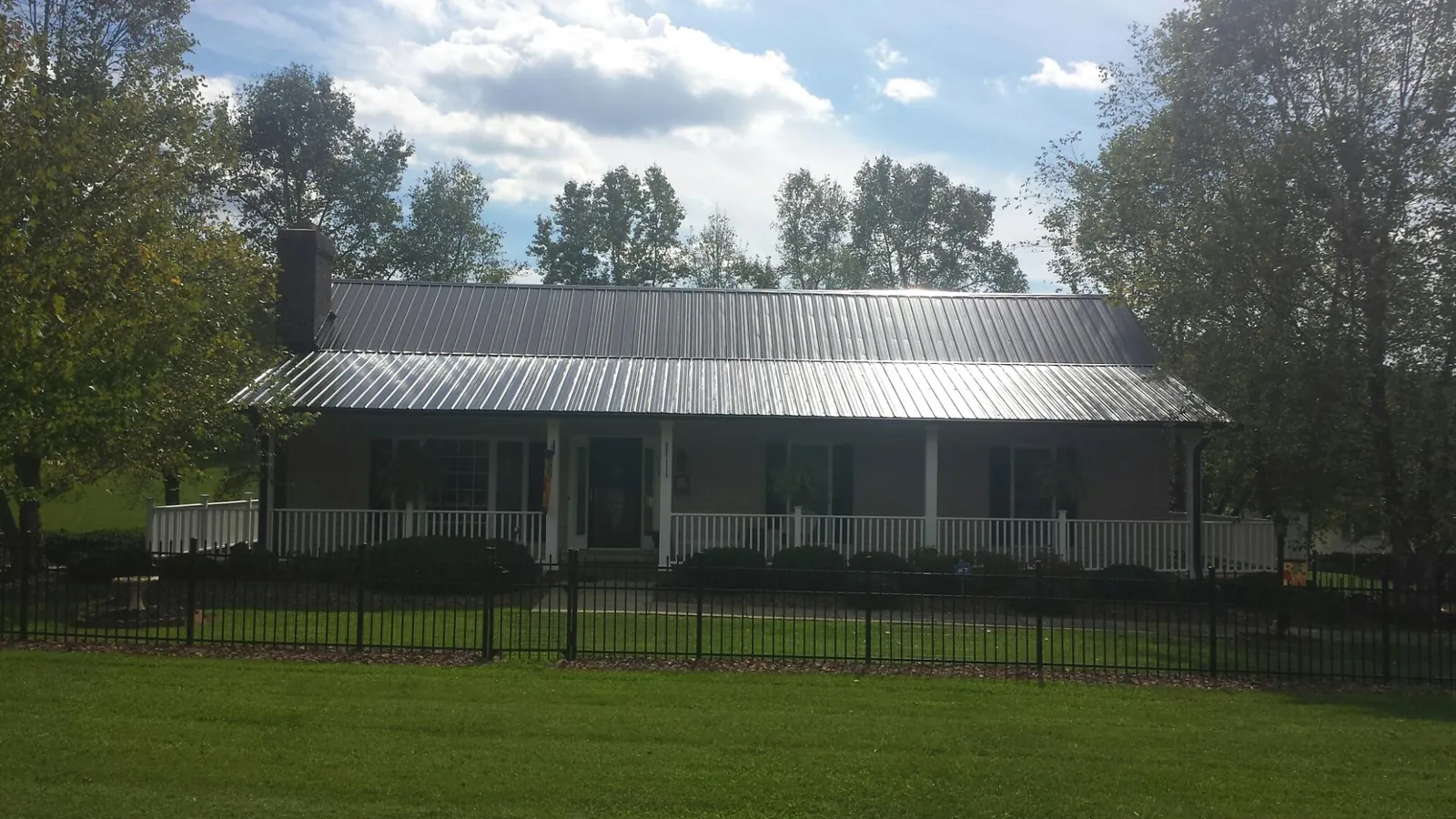 Gray metal roof on a brick ranch with a full width front porch — Gutter Guard Installation work by our crew in Hazleton